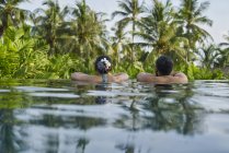 Jovem casal asiático de turistas relaxando em uma piscina — Fotografia de Stock