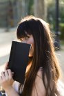 Young Eurasian woman peaking over the book — Stock Photo