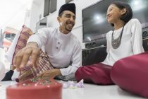 Happy asian family celebrating hari raya at home and playing traditional game — Stock Photo