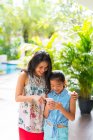 Happy asian woman and daughter using smartphone together — Stock Photo