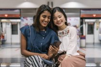 Young casual asian girls using smartphone — Stock Photo
