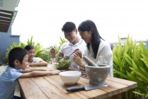 Счастливая азиатская семья готовит еду вместе на дому — стоковое фото