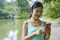 Портрет женщины средних лет, слушающей музыку во время прогулки по Ботаническому саду — стоковое фото