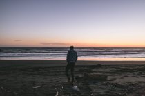 Rückansicht eines jungen Mannes, der an einem Strand in Neuseeland spaziert — Stockfoto