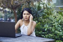 Молодая малайская женщина расстроена, когда работает над своим ноутбуком на открытом воздухе — стоковое фото