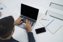 Молодий азіатський бізнесмен працює з ноутбуком в сучасному офісі — стокове фото
