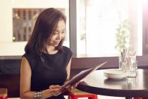 Giovane bella donna asiatica guardando il menu in caffè — Foto stock