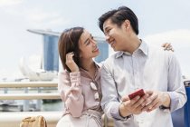 Jovem asiático casal compartilhamento smartphone juntos em Cingapura — Fotografia de Stock