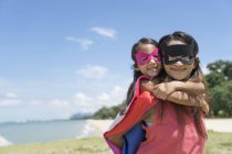 Mutter trägt Superhelden-Kind am Strand zurück — Stockfoto