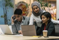 Jovens empresários multiculturais que trabalham com dispositivos digitais em escritórios modernos — Fotografia de Stock