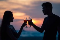 Attractive young asian couple having drink at sunset — Stock Photo