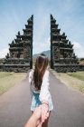 Visão traseira da jovem senhora segurando a mão de seu parceiro em Bali — Fotografia de Stock