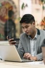 Молодой азиатский бизнесмен, использующий смартфон в современном офисе — стоковое фото