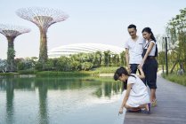 Familia curiosa sobre el lago en Gardens by the Bay, Singapur - foto de stock