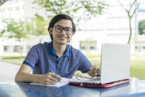 Estudante malaio trabalhando no projeto da escola no laptop — Fotografia de Stock