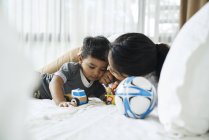 Madre e figlio giocare con i giocattoli sul letto — Foto stock