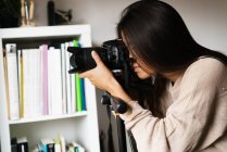Chinese woman taking photo with camera indoors, closeup — Stock Photo