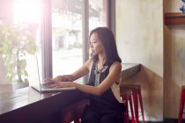 Молода красива азіатська жінка використовує ноутбук у кафе — стокове фото