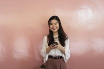 Молодая случайная азиатская девушка с помощью смартфона — стоковое фото