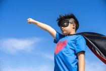 Superhéroe niño contra el fondo del cielo azul . - foto de stock