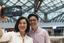 Jeune casual asiatique couple prise selfie à shopping centre commercial — Photo de stock