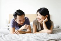 Mature asian casual couple lying on bed together — Stock Photo