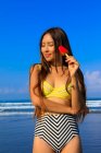 Asian girl on a beach in bikini with an ice cream in her hand. — Stock Photo