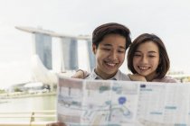 Young asian couple looking at map in Singapore — Stock Photo