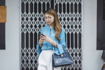 Attractive young asian girl using smartphone — Stock Photo