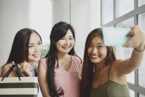 Lindo asiático las mujeres tomando selfie con compras bolsas - foto de stock