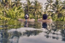 Вид сзади молодой пары, отдыхающей в бассейне — стоковое фото