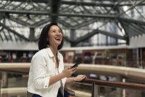 Junge lässige asiatische Frau benutzt Smartphone in Einkaufszentrum — Stockfoto