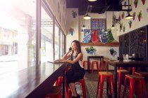 EIGENSCHEIBUNG Junge schöne asiatische Frau benutzt Smartphone im Café — Stockfoto