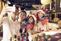 Companhia de jovens amigos asiáticos juntos celebrando o Natal e tirando selfie — Fotografia de Stock