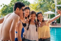 Attrayant jeunes amis asiatiques prendre selfie près de la piscine — Photo de stock