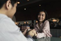 Jovem asiático casal segurando as mãos no bar — Fotografia de Stock