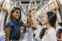 Молодые случайные азиатские девушки улыбаются в поезде — стоковое фото