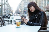 Женщина в кафе со своим смартфоном — стоковое фото