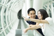 Young attractive asian couple together pointing on something — Stock Photo