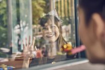 Jovem asiático mulher olhando através de janela no amigo — Fotografia de Stock