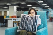Young asian business woman holding pillow in modern office — Stock Photo