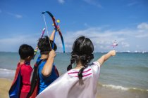 Vue arrière du superhéros Enfants avec des jouets contre la mer — Photo de stock