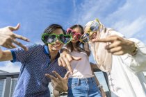 Grupo de amigos con gafas divertidas divirtiéndose contra el cielo azul - foto de stock