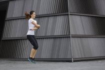 Uma jovem mulher asiática está se exercitando com salto de corda, ao ar livre em Cingapura . — Fotografia de Stock