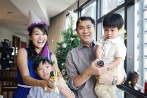 Familia asiática celebrando vacaciones de Navidad con serpentina - foto de stock