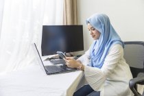 Eine junge Muslimin, die von zu Hause aus arbeitet. — Stockfoto