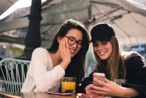 Chinês e europeu mulheres bonitas olhando para o smartphone em um terraço de Madrid — Fotografia de Stock