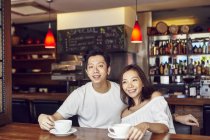 Happy young asian couple having date in cafe — Stock Photo