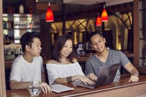 Junge asiatische Freunde mit Laptop zusammen in bar — Stockfoto