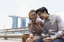 Jovem asiático casal usando smartphone em Cingapura — Fotografia de Stock